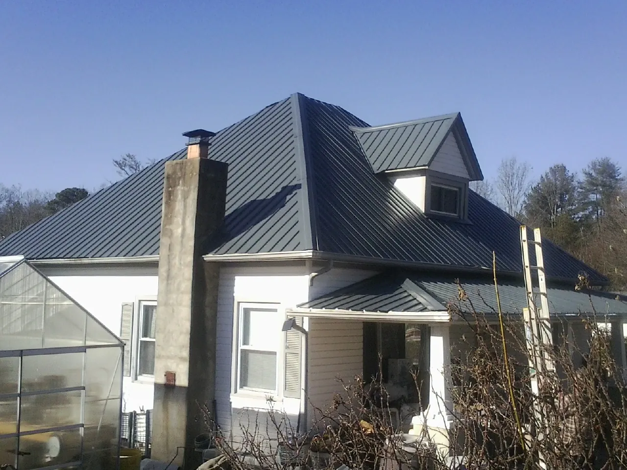 Dark blue standing seam metal roof on a white farmhouse with dormer — Slate & Tile Roof Repair by Roofing Brothers in North Dighton