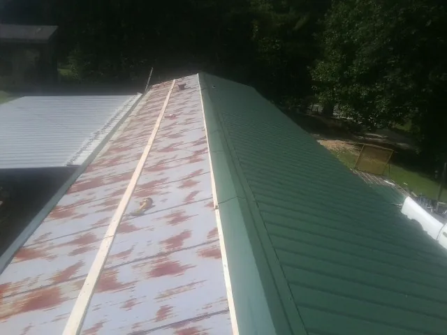 Old rusted panels beside newly installed green metal roofing — Wind Damage Roof Repair by Roofing Brothers in North Dighton