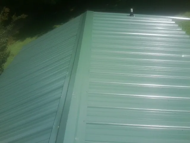 New green metal panels meeting at the ridge of a roof — Flat Roof Repair work by our crew in North Dighton